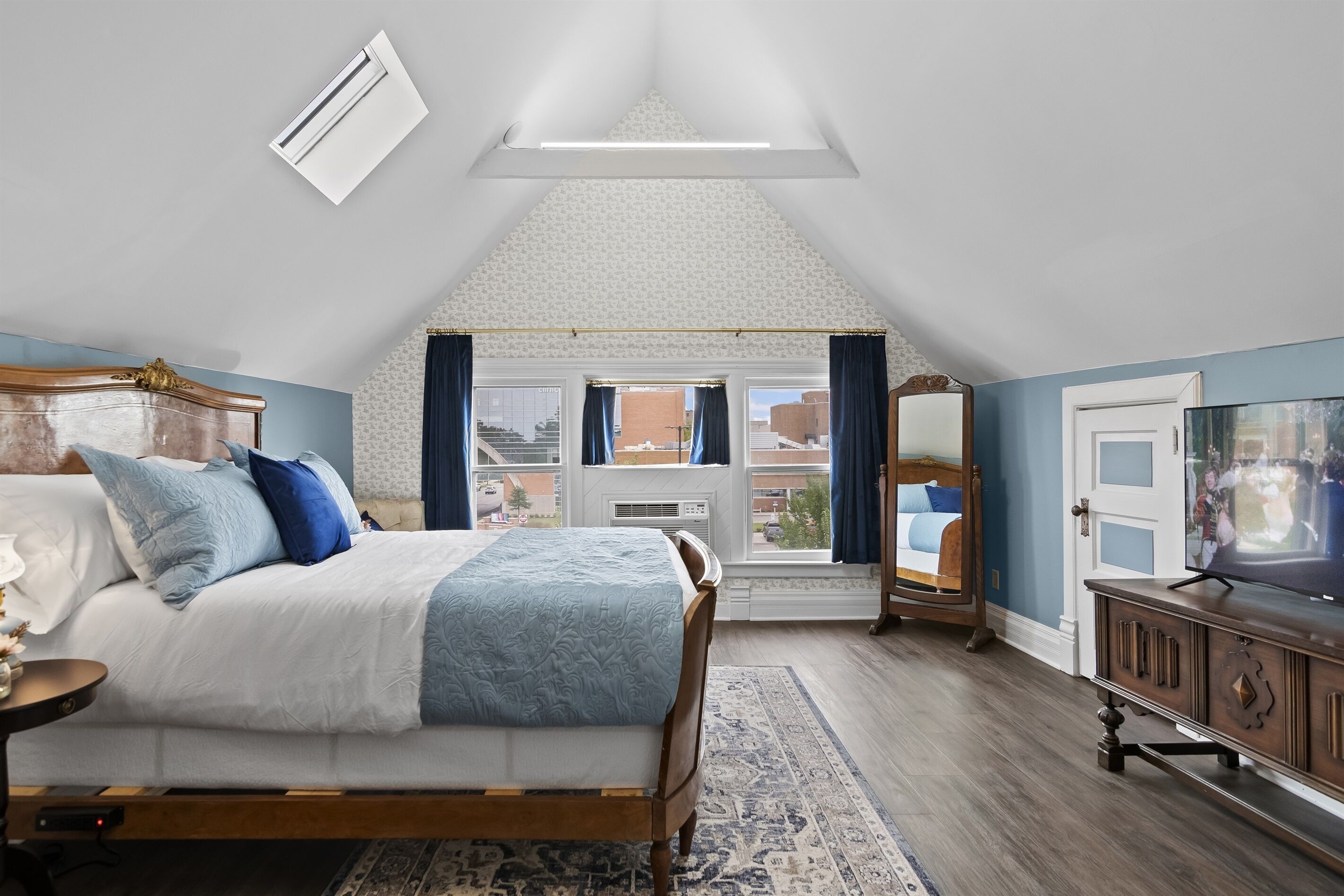 Ein Schlafzimmer mit Bett, Fernseher, Fenster und Blick ins Freie.