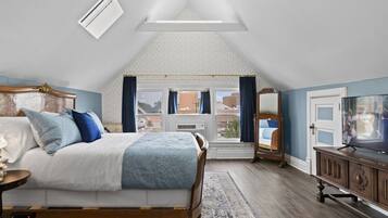 Ein Schlafzimmer mit Bett, Fernseher, Fenster und Blick ins Freie.