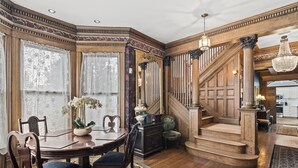 A grand dining room with a wooden staircase, ornate columns, and a chandelier. - Historic Luxury Stay | Downtown Springfield | Step-Free Access (Springfield)