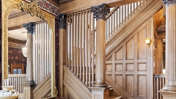 A grand staircase with ornate woodwork and a large mirror. - Grand Historic Retreat | Walk to Capitol & Attractions | Timeless Elegance (Springfield)