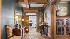 A hallway with wooden flooring, a patterned rug, a wooden bench, a table with a lamp, and a mirror. - Grand Historic Retreat | Walk to Capitol & Attractions | Timeless Elegance (Springfield)