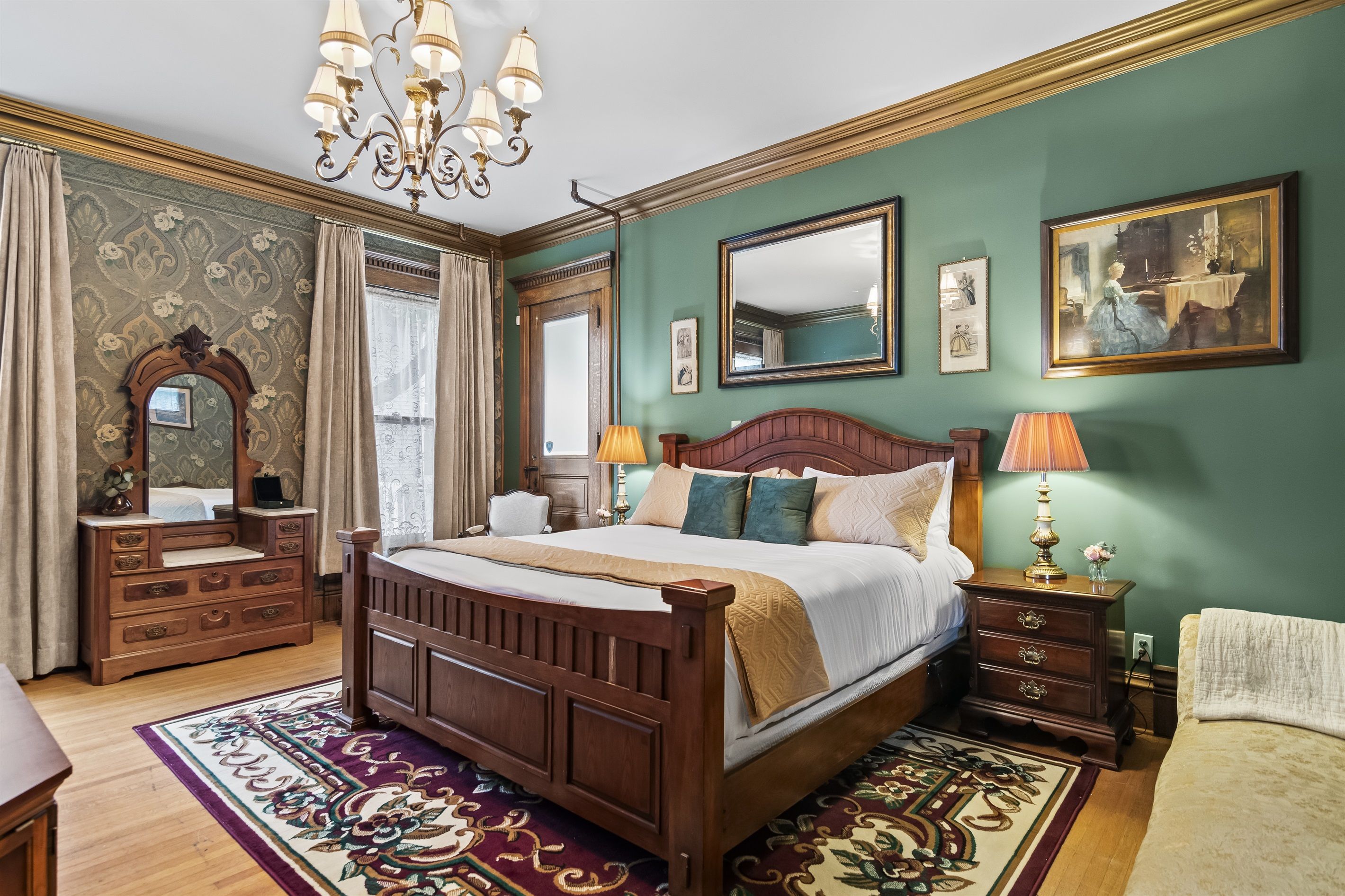 A bedroom with a large wooden bed, a dresser, a mirror, and a chandelier.