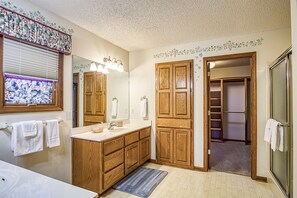 Bathroom features a shower area, vanity, and large mirror.