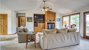 Un salon comprenant un canapé, une table basse, un téléviseur, des meubles en bois et un ventilateur de plafond.