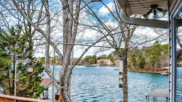 Une vue sur le lac depuis un balcon doté d’une balustrade, avec des arbres et un quai.