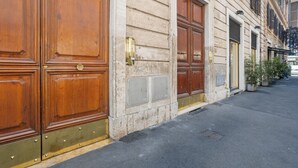 A building with large wooden double doors, a stone facade, and a narrow street.