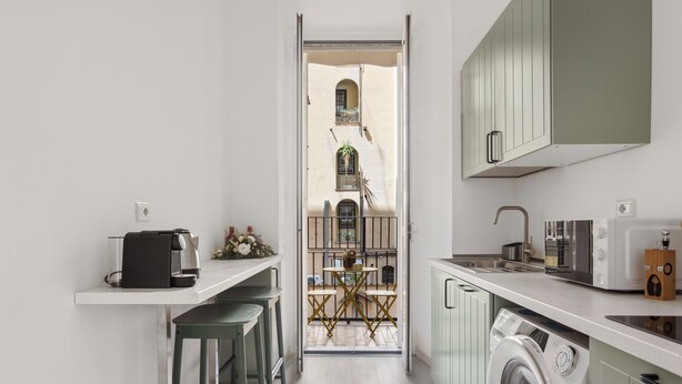 A narrow kitchen with a washing machine, a coffee maker, and a sink.
