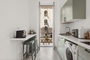 A narrow kitchen with a washing machine, a coffee maker, and a sink.