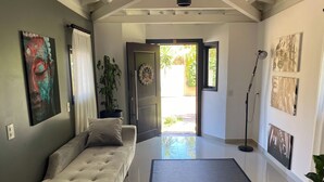 A modern living room with a sofa, a large rug, and artwork on the walls. - Casa de Praia com Trilha Privativa em Condomínio Fechado (Florianópolis)