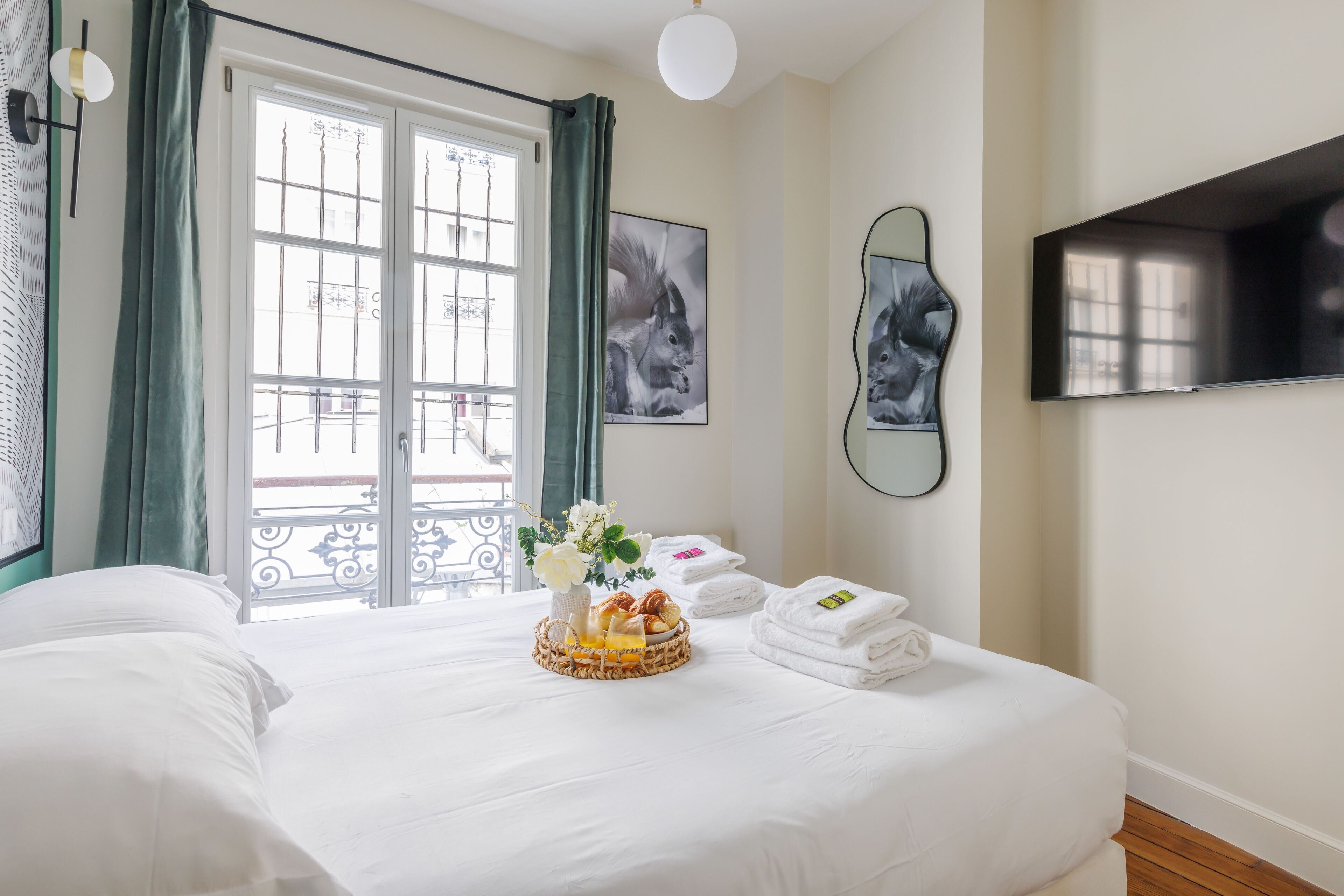 A hotel room with a large bed, a TV, and a window with curtains.
