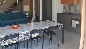 A modern kitchen with a dining area, a staircase, and a living room with a sofa.