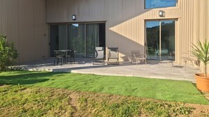 A modern building with a covered patio area featuring outdoor seating and a potted plant.