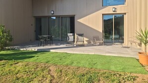 A modern building with a covered patio area, outdoor seating, and a well-maintained lawn. - Zanzimare Casa Paolu_t2 (Eccica-Suarella)