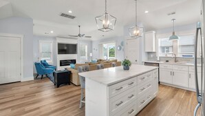 A modern kitchen with white cabinetry, a central island, and pendant lighting.