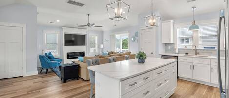 Una cocina moderna con armarios blancos, una isla central e iluminación colgante.