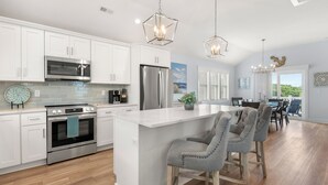 A modern kitchen with white cabinets, stainless steel appliances, and a central island with bar stools.
