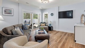 A spacious living room with a large sectional sofa, a coffee table, and a television mounted on the wall.