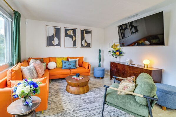 Relax in this stylish living room with a vibrant sofa, flat-screen TV, and beautiful artwork.