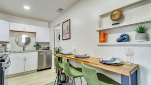A modern kitchen with white cabinets, a wooden countertop, green chairs, and a dining table set for two. - Albuquerque Retreat w/ Hot Tub - Central Location! (Albuquerque)