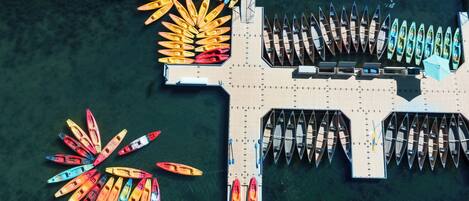 Vista aérea de um cais com vários canoas e caiaques dispostos em fileiras.