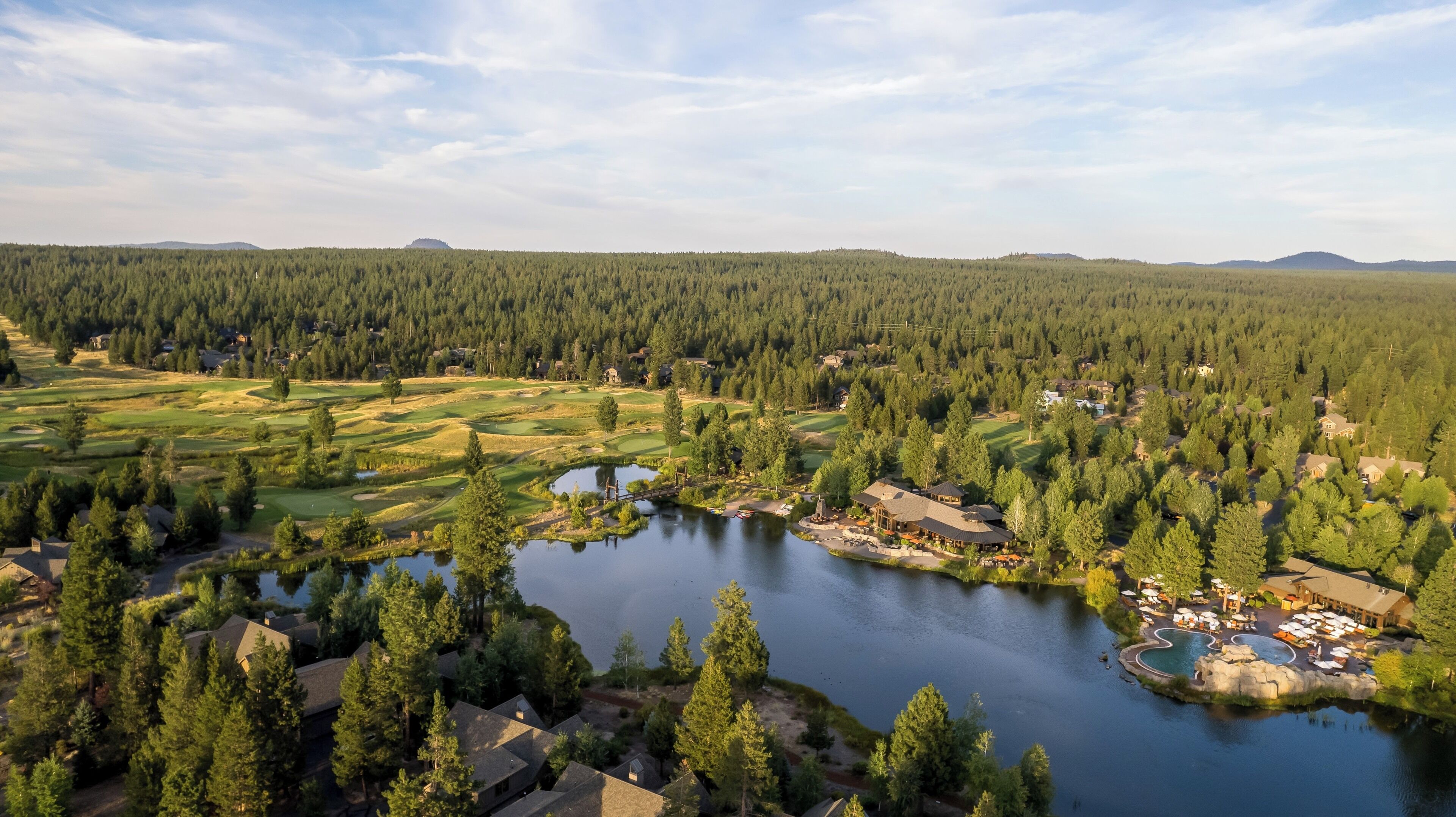 Golfkenttä, jonka yhteydessä on järvi, ja jota ympäröi tiheä metsä sekä asuinrakennuksia.