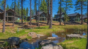 A lakeside cabin with a small stream, surrounded by tall pine trees. - Forestbrook Escape with Access to Forest House (Sunriver)
