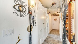A hallway with a wooden floor, a wall-mounted eye sculpture, and a mirror. - Tucson Retreat w/ Fire Pit: 4 Mi to Downtown! (Tucson)