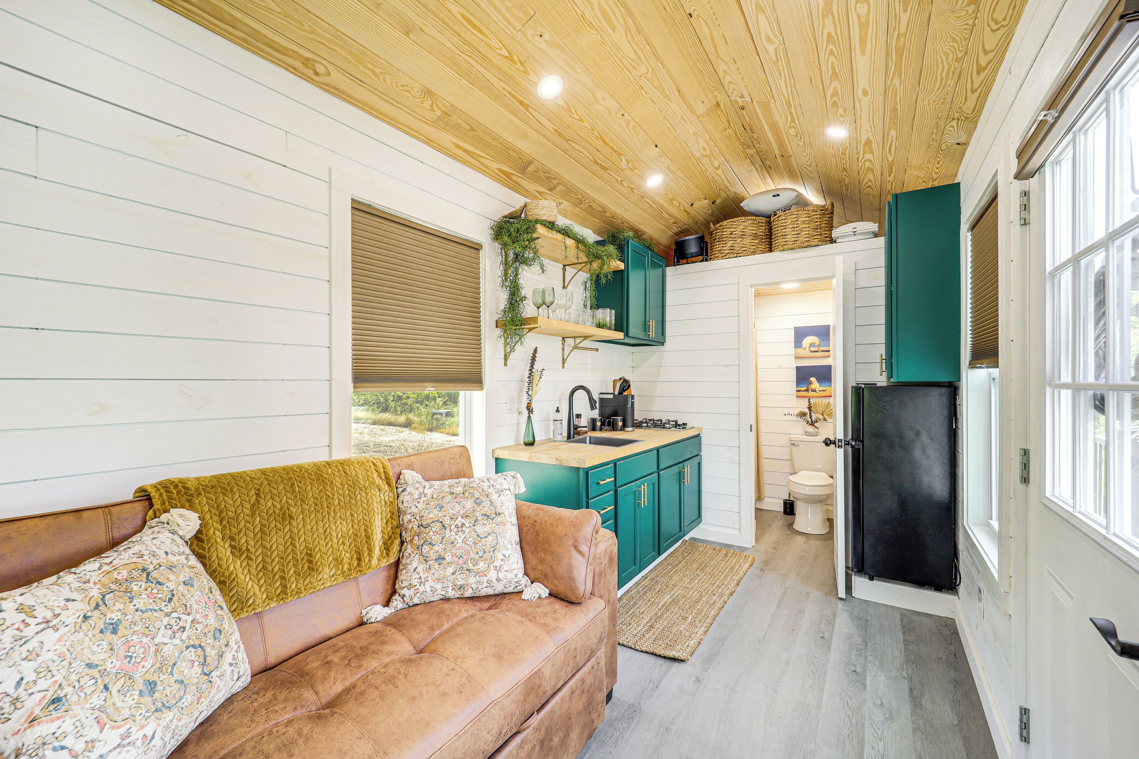 Un intérieur chaleureux avec un canapé en cuir marron, des meubles de couleur turquoise et un plafond en bois.