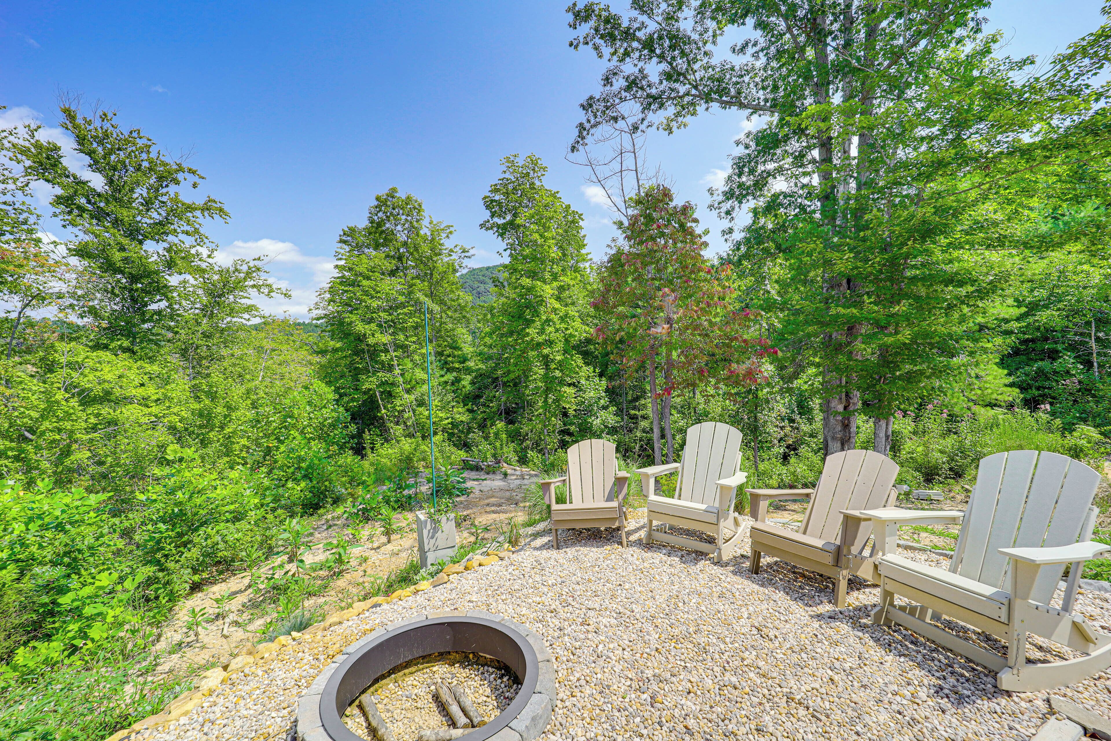 A fire pit area with Adirondack chairs and a gravel ground.