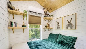 Une chambre avec une couvre-lit turquoise, des étagères en bois ornées d’objets décoratifs et des tableaux représentant des lapins accrochés au mur.