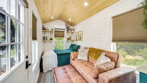 L’intérieur chaleureux d’un chalet avec un plafond en bois, un canapé en cuir marron et une couverture verte sur le lit.