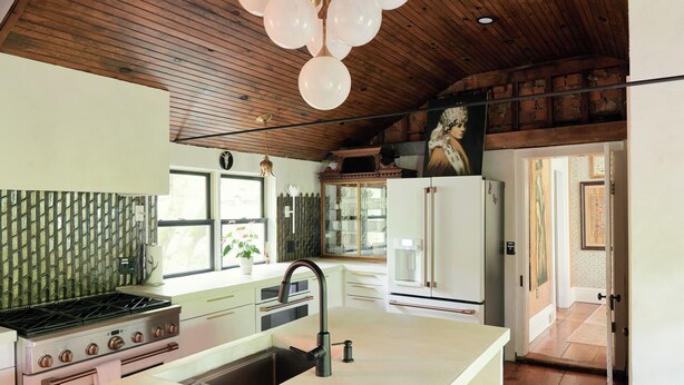 Una cucina con isola centrale, soffitto in legno e vista sull'area pranzo.