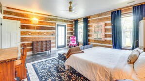 Ein schlafzimmer im Stil einer Blockhütte mit einem großen Bett, einer Holzkombination, einem Sessel und einem Schreibtisch.