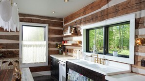 Eine rustikale Küche mit Holzwänden, einem großen Fenster und einem Spülbecken mit Fenster darüber.