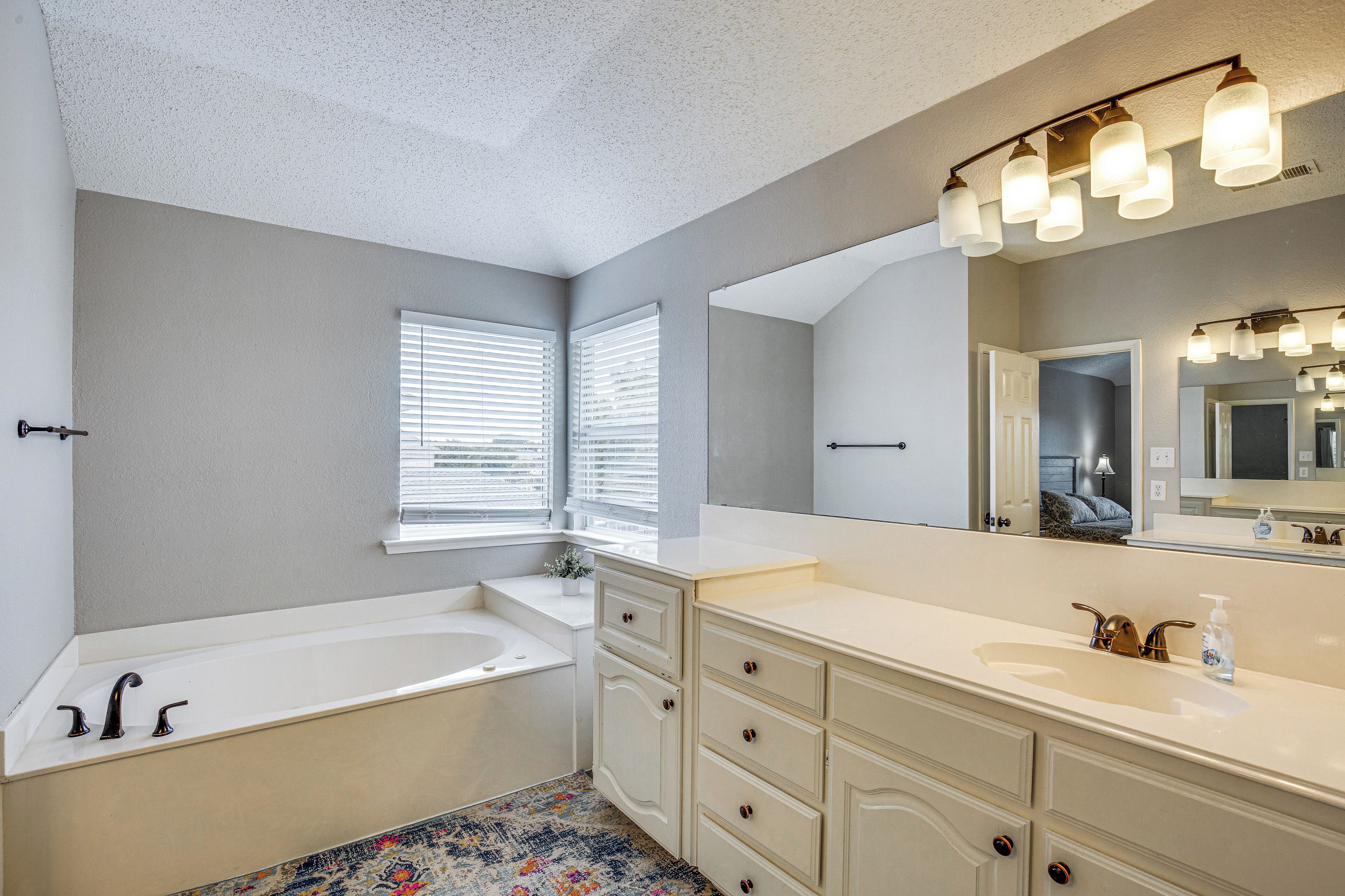 A modern bathroom with a bathtub, vanity, and large mirror.