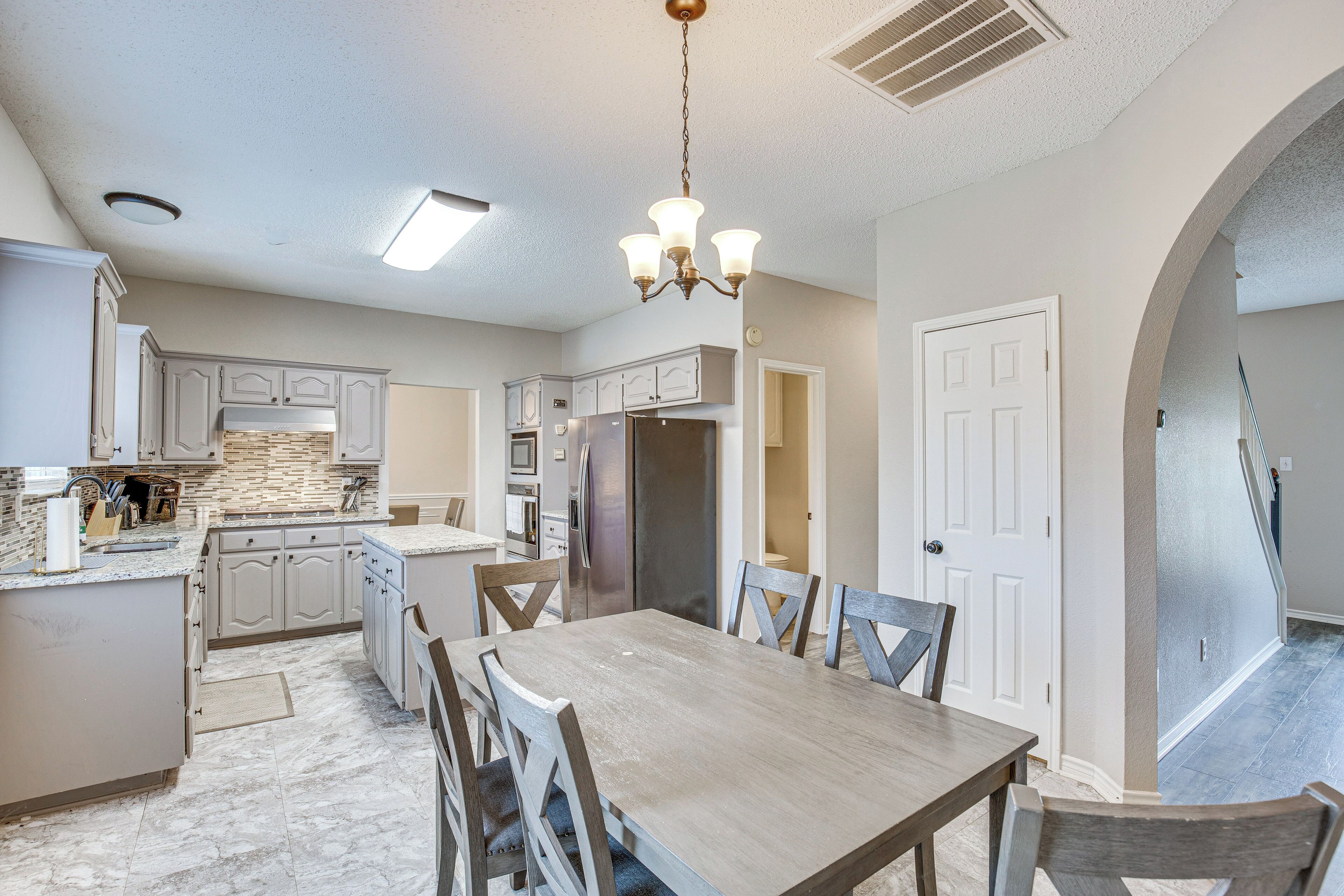 A modern kitchen with a central island, built-in appliances, and a dining area with a wooden table and chairs.