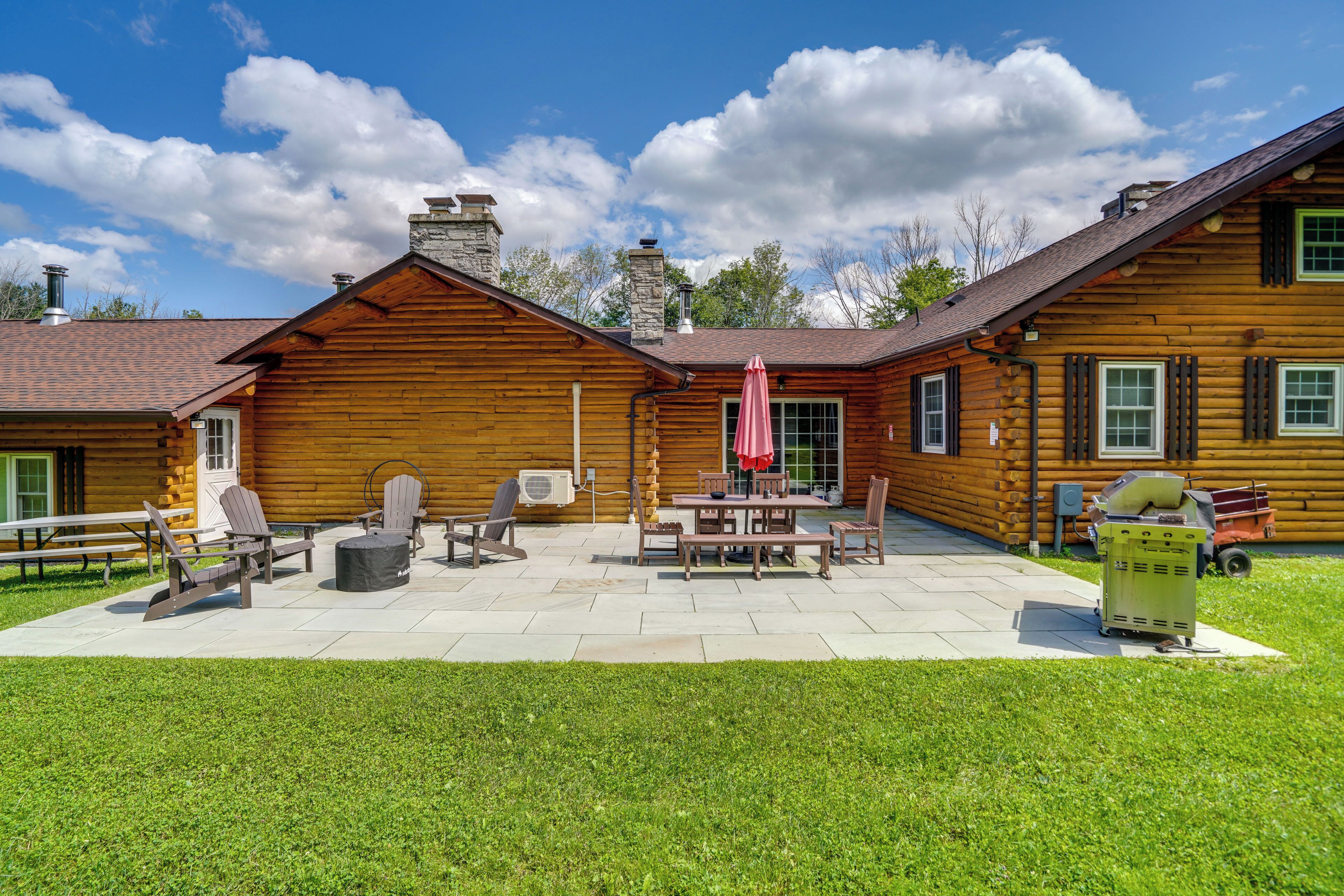 A log cabin with a patio area featuring outdoor furniture and a trash can.
