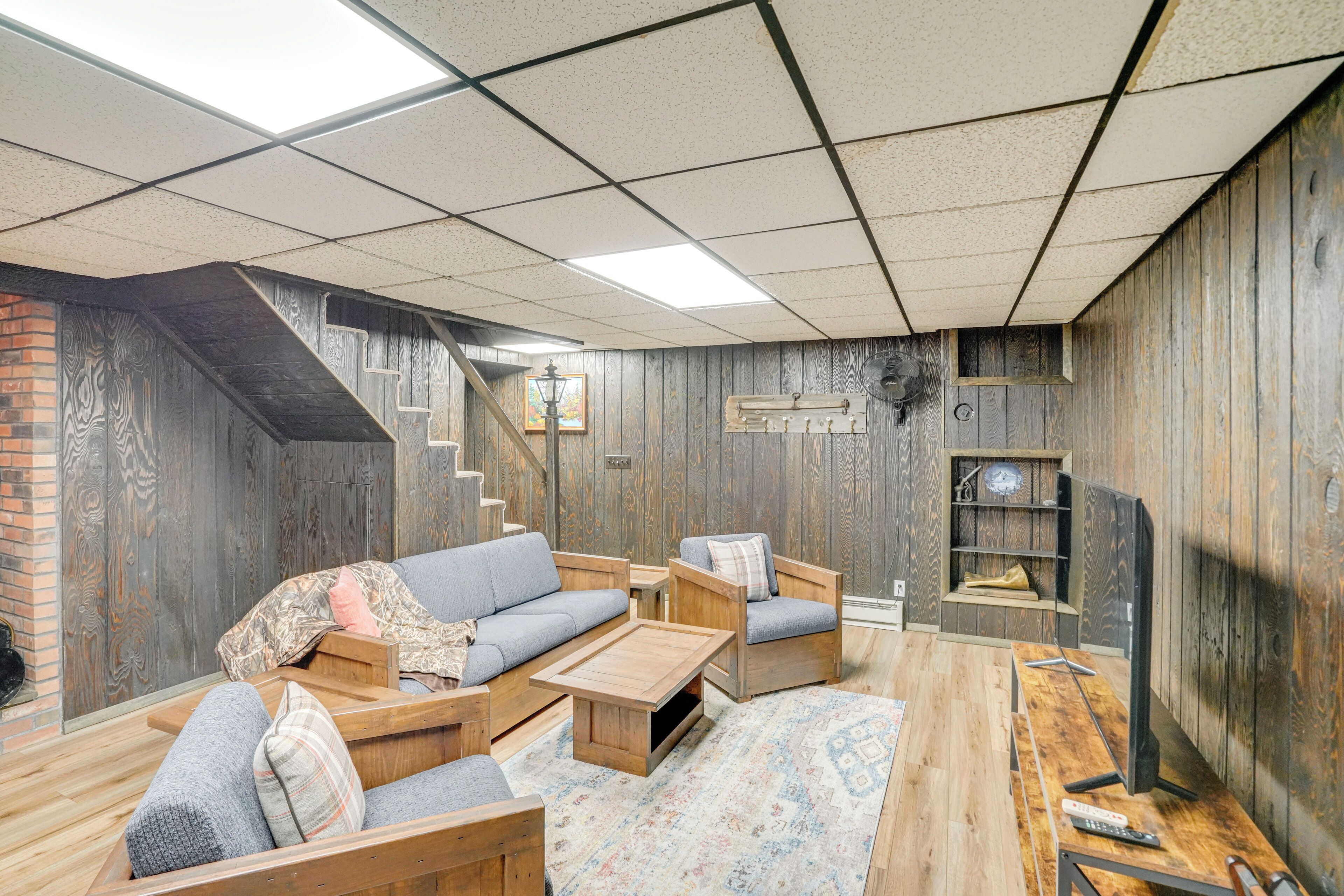 Una sala de estar acogedora con un sofá, sillas, una mesa de centro y un televisor.