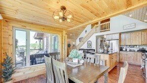 A spacious wooden cabin with a dining area, kitchen, and a staircase leading to a loft. - Lakefront Divide Cabin w/ Game Room! (Woodland Park)