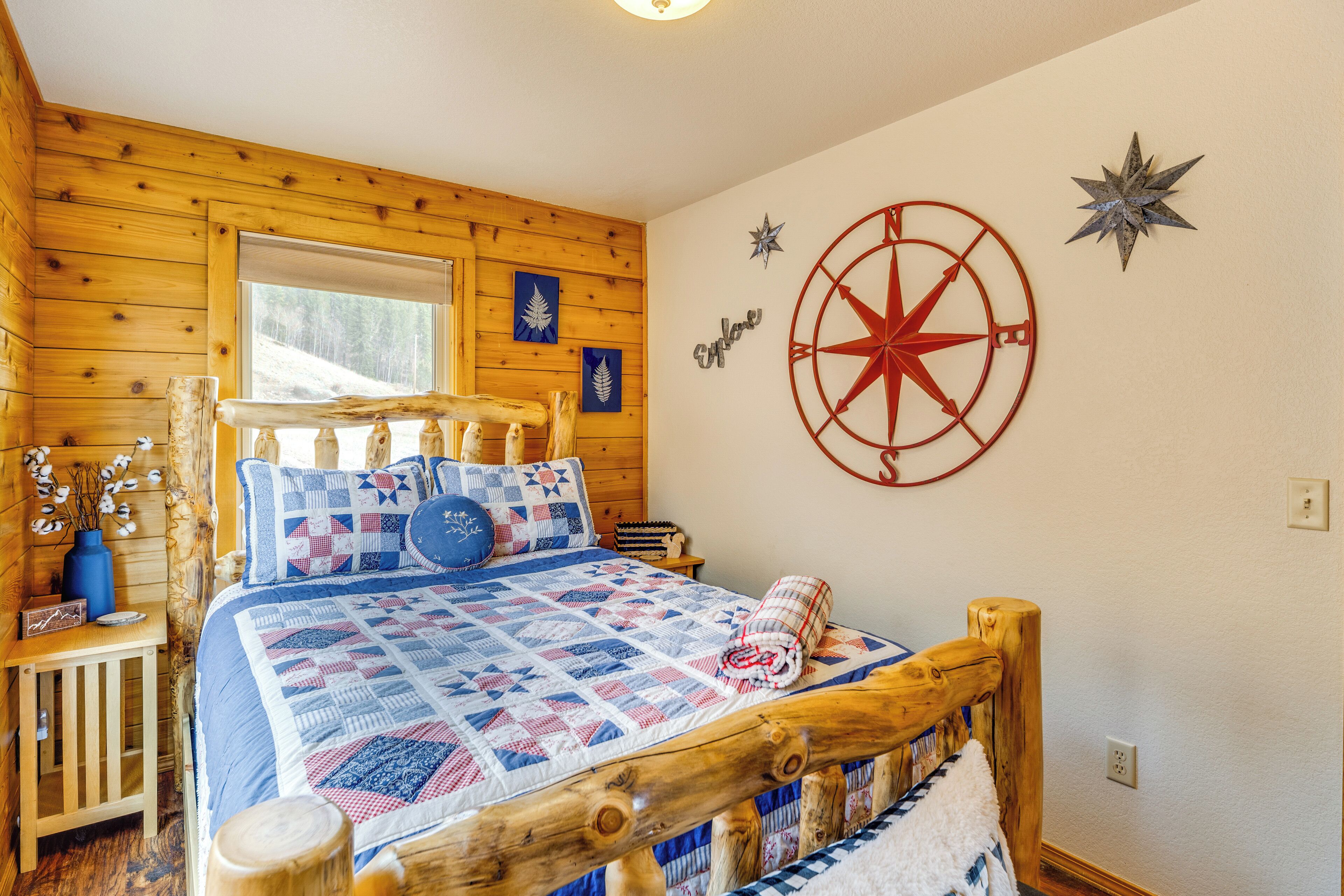 A cozy cabin-style bedroom with a wooden bed, a quilt, and a compass wall decoration.