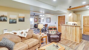 A spacious living room with a brown leather couch, a wooden coffee table, and a fireplace. There is a dining area with a table and chairs, and a kitchen with wooden cabinets. - Cozy Eureka Getaway - Hike, Bike, Hunt & Fish! (Eureka)