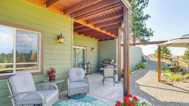 A covered porch with wicker chairs and a table, a green wall, and a view of the outdoors. - Cozy Eureka Getaway - Hike, Bike, Hunt & Fish! (Eureka)