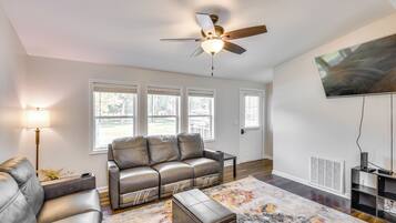 A modern living room with a leather sofa, a coffee table, a floor lamp, and a ceiling fan.