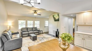A spacious living room with a ceiling fan, a fireplace, and a large window.