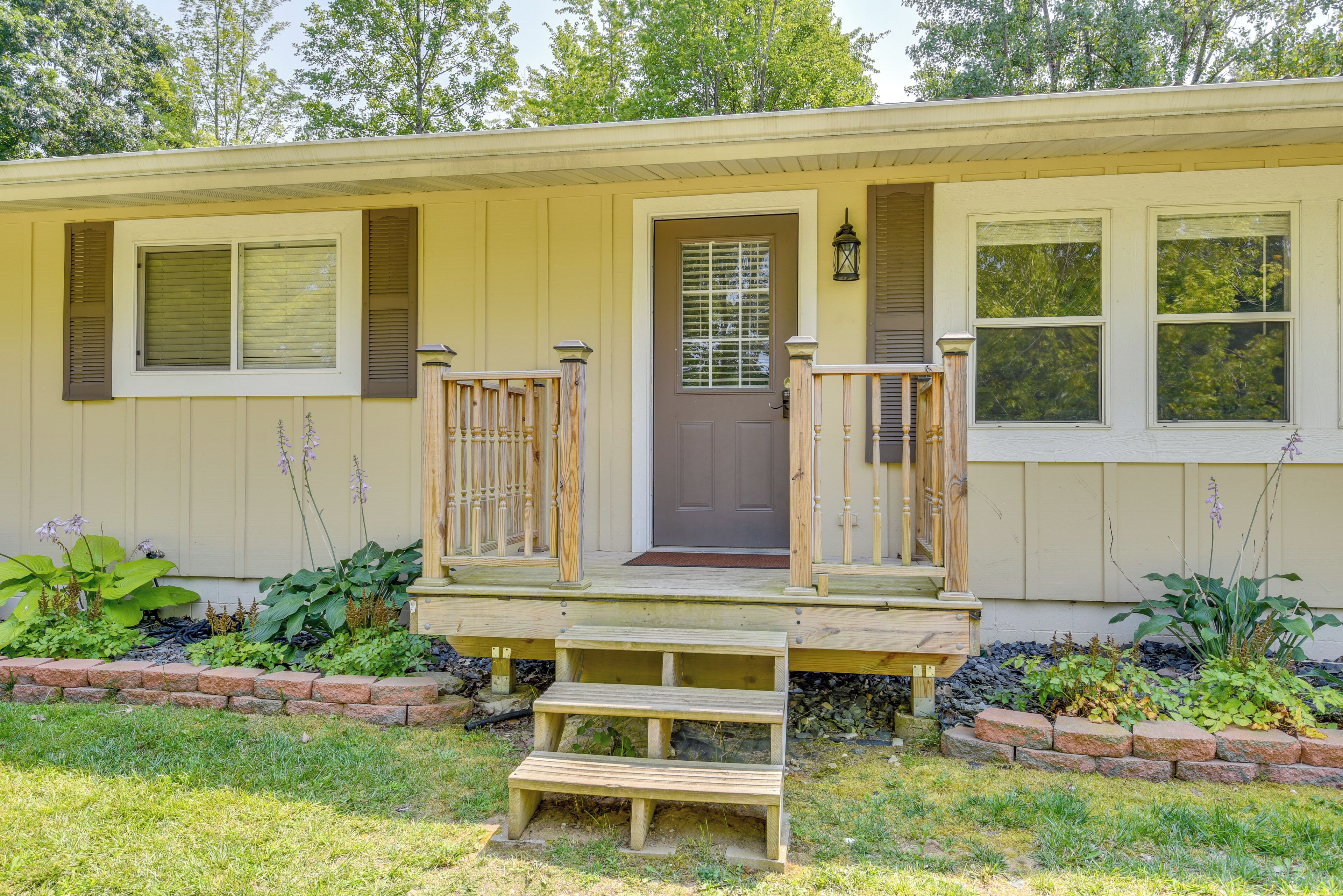 Eenlaags huis met een veranda, een voordeur en een kleine voortuin met planten.