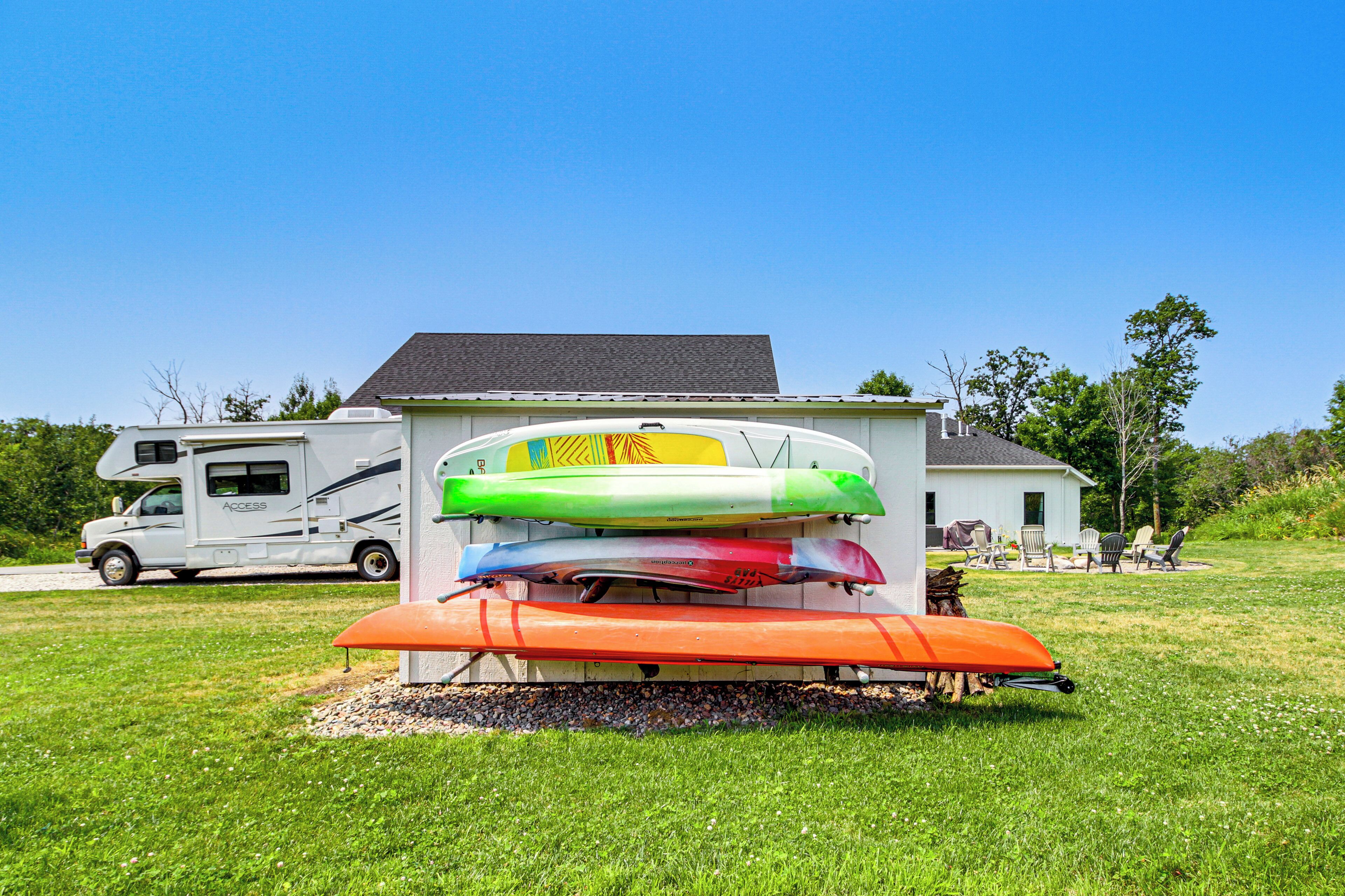 Une rangée de kayaks devant une maison, avec un camping-car garé à proximité.