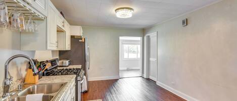 A kitchen with a stainless steel sink, a stove, and a window.