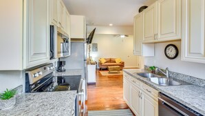 A compact kitchen with white cabinets, a built-in oven, and a granite countertop. - 2 Mi to Warren Dunes - Bright Sawyer Apartment! (Sawyer)