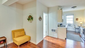 A living room with a yellow sofa, a small side table, and a decorative wall hanging. - 2 Mi to Warren Dunes - Bright Sawyer Apartment! (Sawyer)
