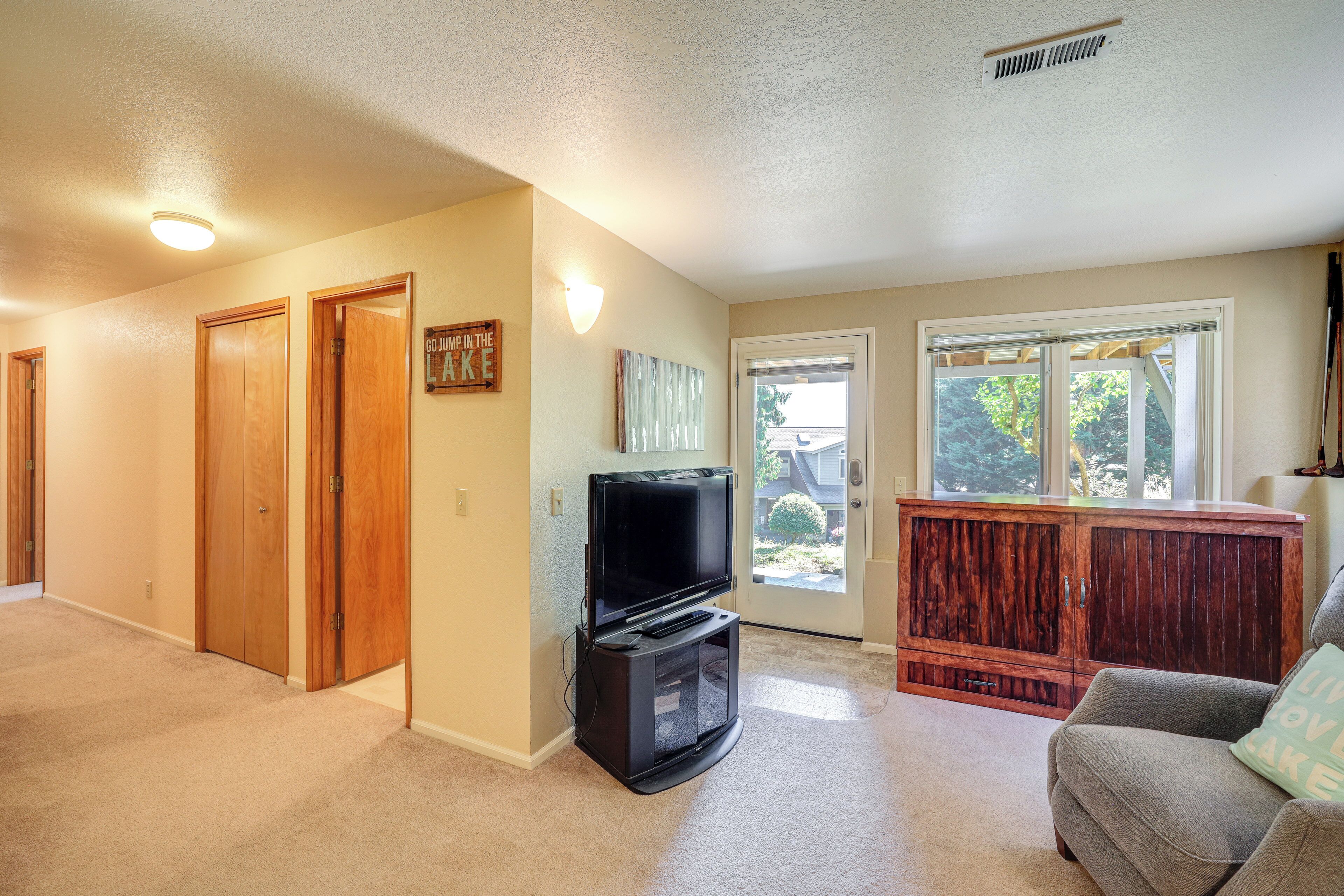 A living room with a television, a gray couch, and a wooden cabinet.